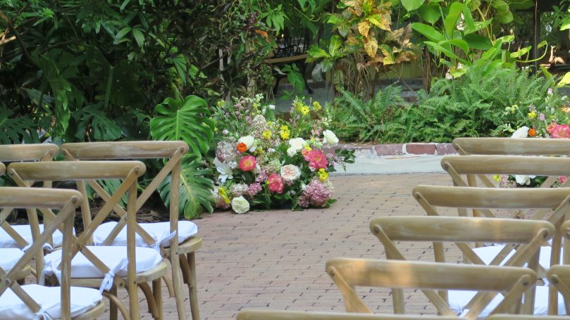 Garden Wedding Ceremony An outdoor wedding setup with chairs and a colorful floral arrangement.