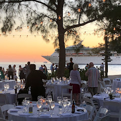 Beach Wedding Beachside event at sunset with tables, guests, and a cruise ship in the background.