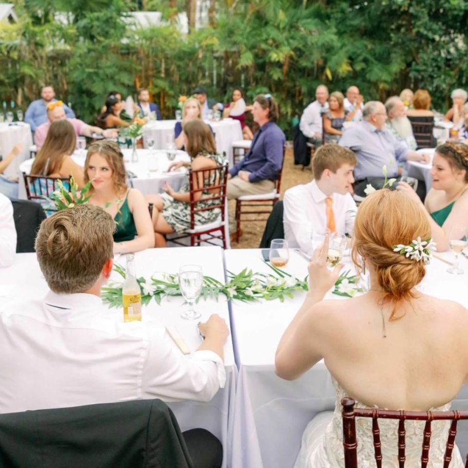 Gathering of guests at a wedding reception with tables set outdoors.