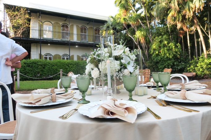 Wedding Table Setting Elegant outdoor dining setup with a floral centerpiece and green glassware.