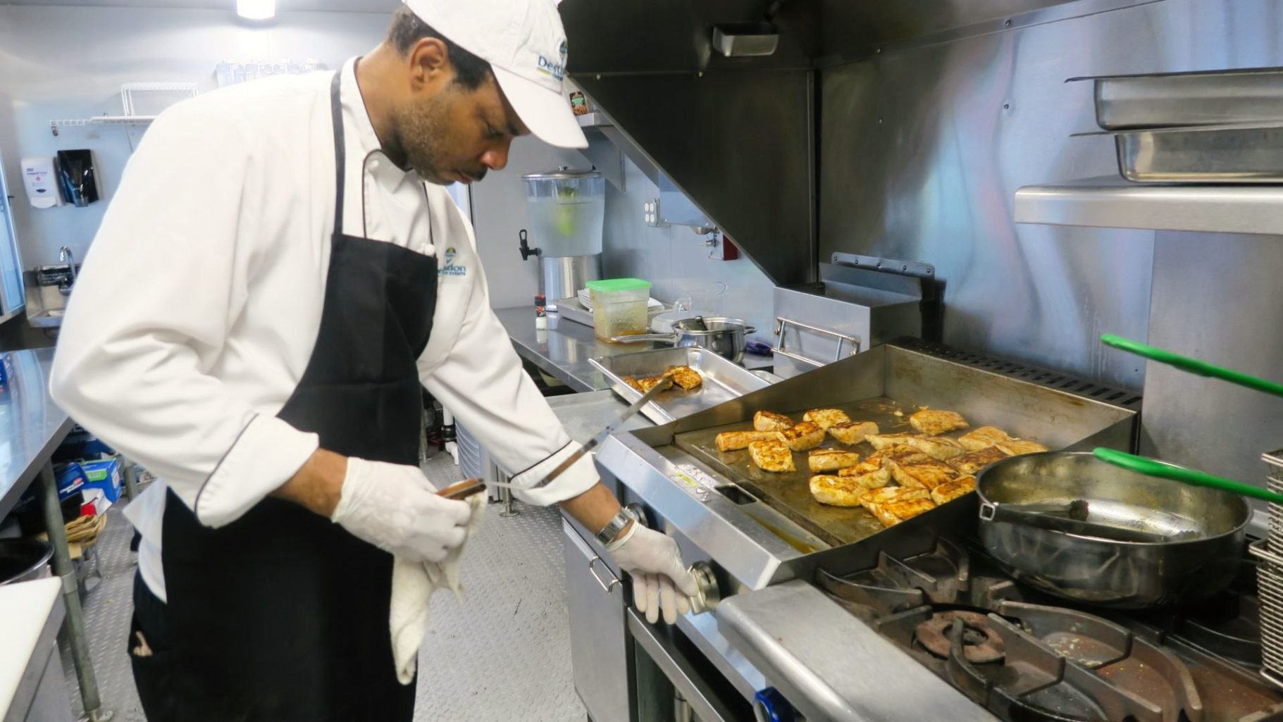 Chef T. on The Grill Chef cooking fish fillets on a grill in a professional kitchen.