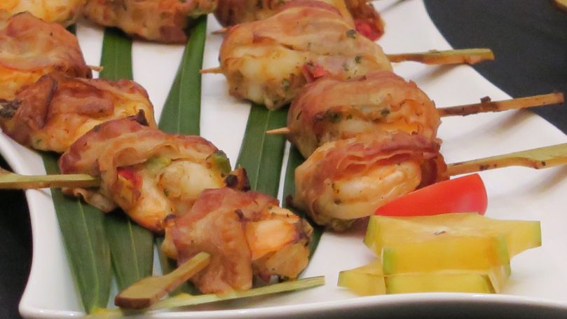 Wedding Cocktail Reception Grilled skewers of shrimp wrapped in bacon on a platter with garnish.