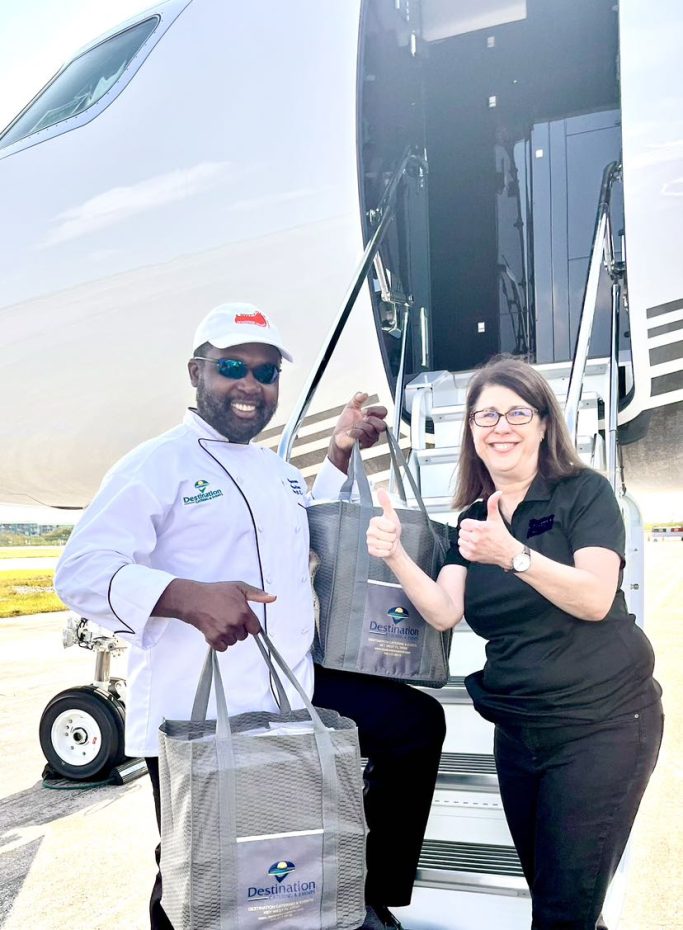 Aircraft Catering Two people hold bags and smile near an airplane staircase on the tarmac.